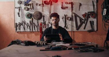 A man is sitting at a table with tools video