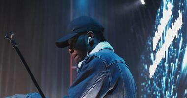 A man in a hat and jacket playing a keyboard video
