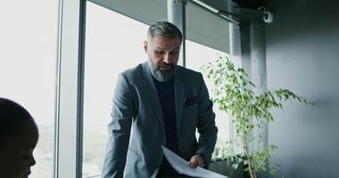 A man in a suit is standing in front of a window video