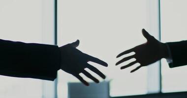 Two people shaking hands in front of a window video