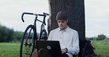 A man sitting on the grass with a laptop video