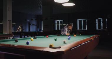 A man is playing pool in a room with a green pool table video