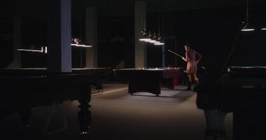 A woman is standing in front of a pool table video