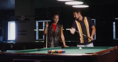 A man and woman playing pool in a bar video