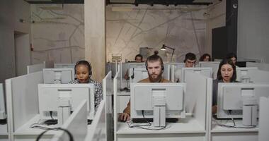 A group of people sitting at computers in an office video