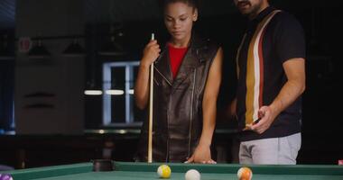 A man and woman standing next to a pool table video