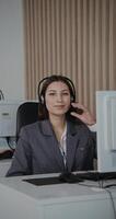 A woman wearing a headset in front of a computer video