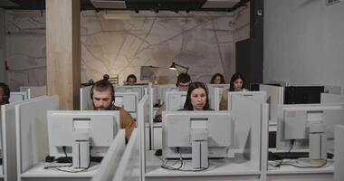 A group of people sitting at computers in an office video