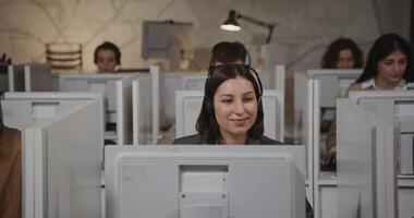 A woman is sitting at a desk in front of a computer video