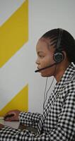 A woman wearing a headset and headphones in front of a computer video