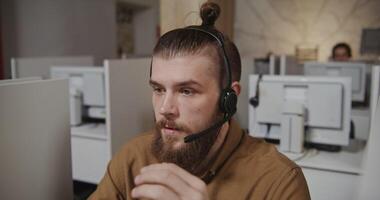 A man with a beard wearing a headset in an office video