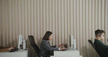 Three people sitting at computers in an office video