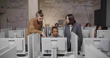 A man and woman are working on computers in a classroom video
