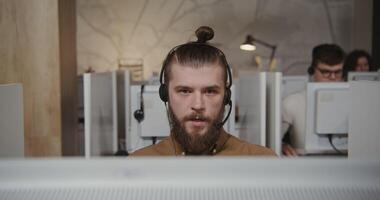 A man with a beard and a headset in front of a computer video