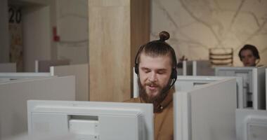A man with a beard and a ponytail is working on a computer video