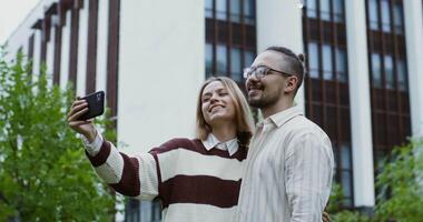 A man and woman taking a selfie in front of a building video