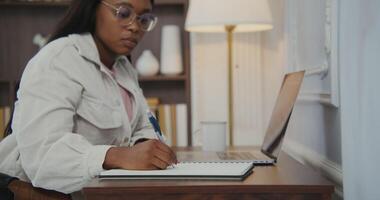 A woman in glasses is writing on a notebook video