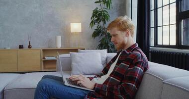 A man sitting on a couch using a laptop video