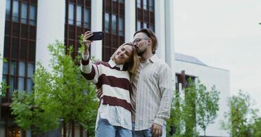 A man and woman taking a selfie in front of a building video