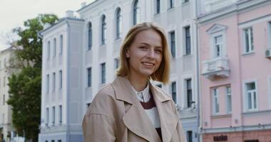 A woman in a trench coat standing in front of buildings video
