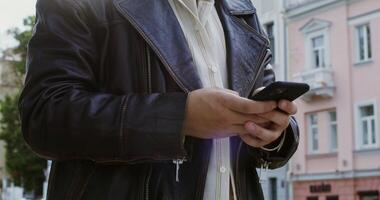 A man in a leather jacket is using his cell phone video