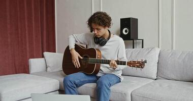 A man playing guitar on a couch video