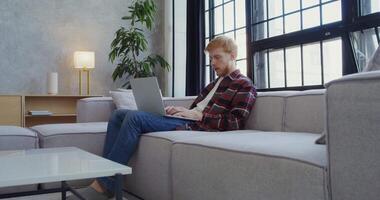 A man sitting on a couch using a laptop video