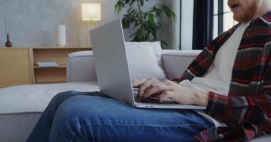 A man sitting on a couch using a laptop video