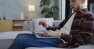 A man sitting on a couch using a laptop video