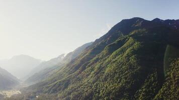 A view of a mountain range with trees and green grass video