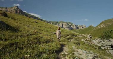 A person walking up a mountain trail with a mountain in the background video