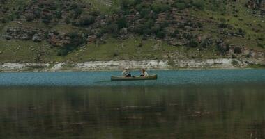 Two people in a canoe on a lake near mountains video