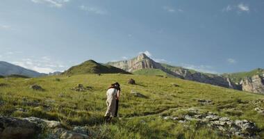 A man standing on a grassy hill with mountains in the background video