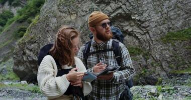 A man and woman with backpacks standing on a rocky hill video