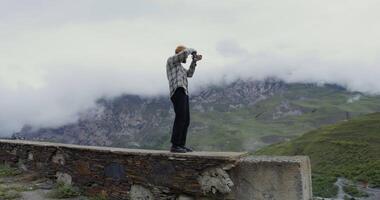 A man standing on a ledge with a camera video