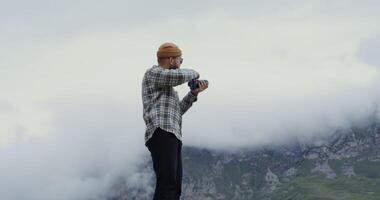 A man standing on top of a mountain with a camera video