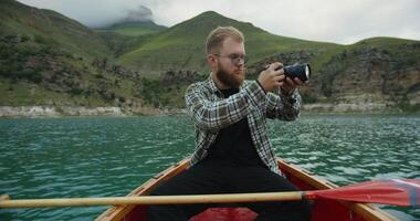 A man in a boat taking a photo with his camera video