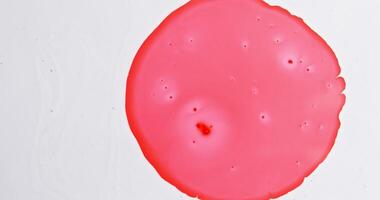 A red liquid is sitting on top of a white surface video