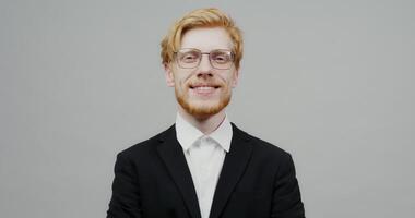 A man with glasses and a red beard is smiling video
