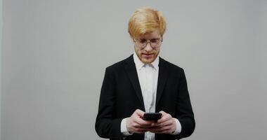A man in a suit and glasses is holding a cell phone video