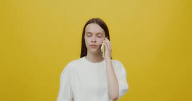 A woman talking on a cell phone while standing on a yellow background video