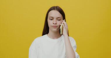 A woman talking on a cell phone while standing in front of a yellow background video