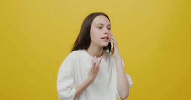 A woman talking on a cell phone while standing on a yellow background video