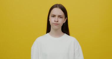 A woman in a white t - shirt is looking at the camera video