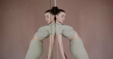 A woman in a green top is standing in front of a mirror video
