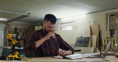 A man is working on a laptop in a workshop video