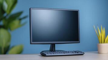 Computer monitor and keyboard on wooden desk with blue wall background photo