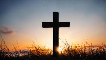 Cross on hill at sunset. Simple wooden cross. Religious symbol in nature. Sky and sun beams behind cross. photo