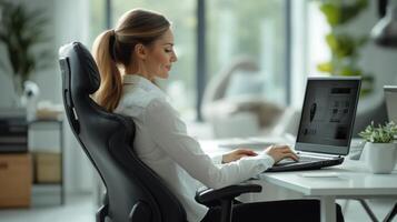 Woman at desk. Business person working. Office worker uses computer. Lady types on laptop. Indoor office space. Modern workplace. Professional environment. photo