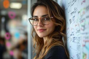 Woman with Glasses Leaning on Whiteboard in Office. Charts and Diagrams on Board. Smiling Female at Work. Modern Business Scene. photo